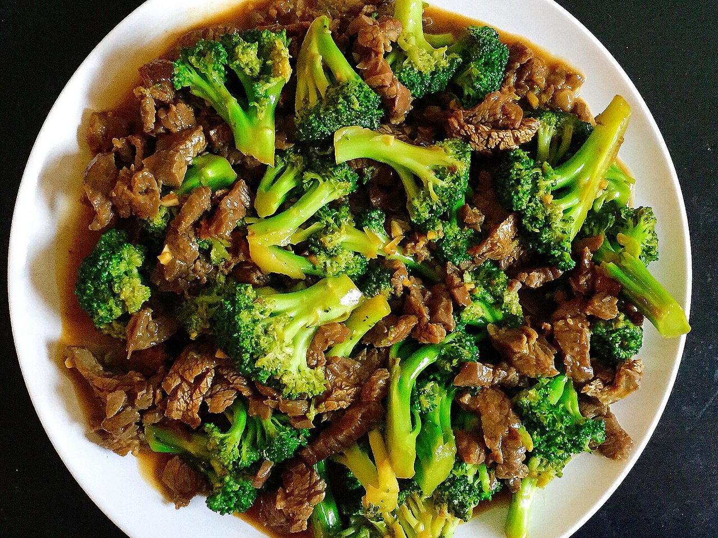 Beef and broccoli in a savory brown sauce, steam rising from a white bowl